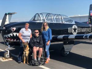K9 Bear and veteran with family in front of world war II fighter plane